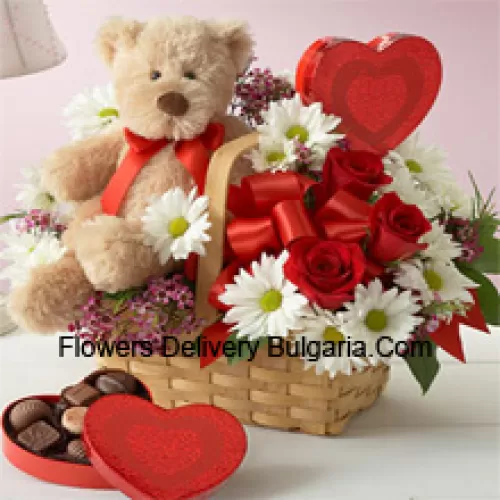 Un beau panier composé de roses rouges, de géraniums blancs et de remplissages saisonniers, une boîte de chocolat importée et un mignon ours en peluche brun