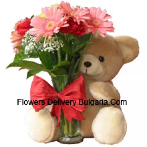11 Oeillets rouges et Géraniums roses dans un vase en verre décoré d'un nœud et accompagné d'un ours en peluche