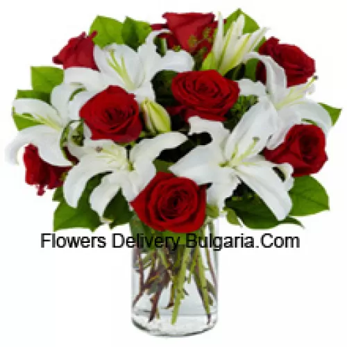 Roses rouges et lys blancs avec des remplissages saisonniers dans un vase en verre