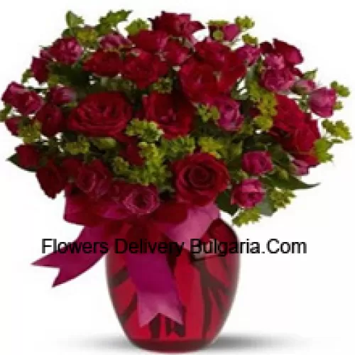 26 roses rouges et 25 roses roses avec quelques fougères dans un vase en verre