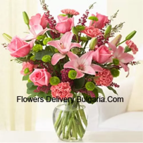 Roses roses, oeillets roses et lys roses avec des fougères assorties et des remplissages dans un vase en verre