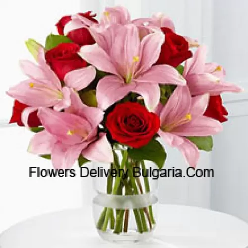 Roses rouges et lys roses avec des garnitures saisonnières dans un vase en verre